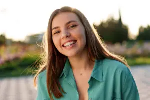 Portrait of young woman in green shirt smiling in a park